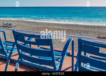 Chaises bleues donnant sur une plage de galets et une mer turquoise calme Banque D'Images