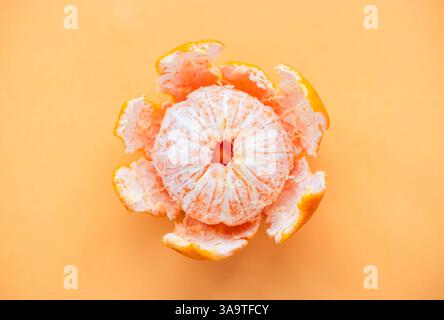 Vue de dessus de clémentine avec peler partiellement sur fond orange. Banque D'Images