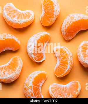 Vue de dessus de nombreux segments de clémentine sur fond orange. Banque D'Images
