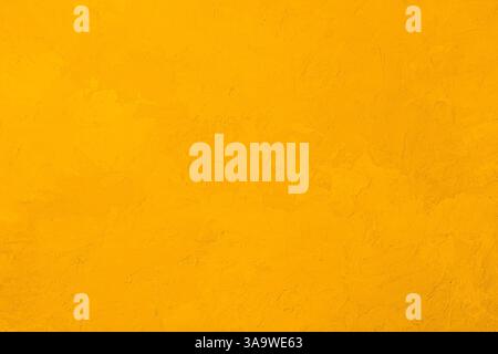 Mur en stuc texturé jaune avec surface de plâtre rugueuse et couleur vive chaude Banque D'Images