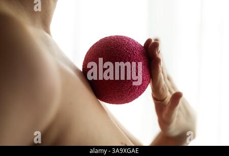 Gros plan de la femme roulant boule de massage sur les côtes avec la paume Banque D'Images