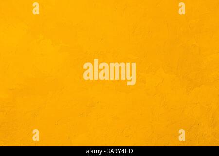 Mur en stuc texturé jaune avec surface de plâtre rugueuse et couleur vive chaude Banque D'Images