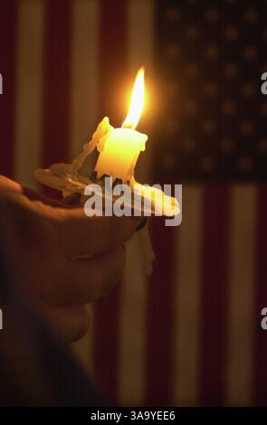 Une bougie solitaire brûle devant un drapeau américain le 14 septembre, jour de deuil national. Cinq mille personnes se sont rassemblées au coucher du soleil sur la promenade River Walk à West Sacramento, le long de la rivière Sacramento, pour se souvenir des victimes de l'attaque du World Trade Center. Tenant des bougies allumées, ils se sont assis sur la digue ou sous les cottonwoods, écoutant les prières des clercs locaux, chantant ''Amazing Grace'' et des chansons patriotiques. (Sacramento Bee photo de Randy Allen) /ZUMA Press Banque D'Images