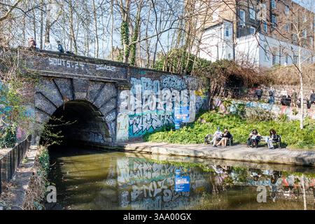Les gens profitent d'un peu de soleil printanier à l'extrémité est du tunnel d'Islington sur Regent's canal à l'Angel. Londres, Royaume-Uni Banque D'Images