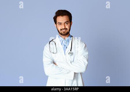 Médecin indien confiant en uniforme croisant ses bras sur fond de couleur Banque D'Images