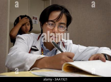 À la clinique HOPE de Sacramento, un programme qui fonctionne 2 fois par mois pour donner des soins médicaux aux familles sans-abri, Jean Sakimura (CQ), pédiatre résidente de l'hôpital pour enfants de l'UCD, regarde les cartes mercredi après-midi 12 juin 2002 alors qu'elle s'apprête à examiner 3 des enfants de Roberta Bernardino dont l'un est Rebecca Bernardino (CQ) âgée de 8 ans en arrière-plan de la photo. L'Hôpital pour enfants UC Davis a lancé un programme novateur pour que les pédiatres suivent une formation à l'extérieur du bureau et prennent soin des enfants de la communauté. Le programme est le premier du genre dans le pays, fournissant des résidents Banque D'Images
