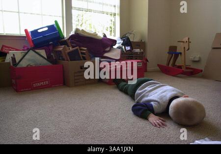 Mason Graham, 2 ans, repose momentanément sur le sol dans le salon près d'une pile de boîtes emballées, jeudi 21 février 2002. Sa famille fait partie des 420 locataires qui ont reçu un avis d'expulsion de 30 jours de la part de l'investisseur japonais Genshiro Kawamoto. Sa mère, Donna Graham, dit que c'est une période stressante pour ses enfants et qu'elle aurait souhaité qu'on lui donne plus de temps pour les préparer au déménagement. Sacramento Bee/Lezlie Sterling The Sacramento Bee/ZUMA Press Banque D'Images
