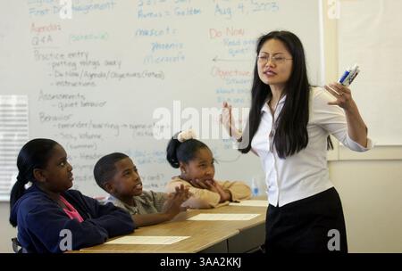 Geraldine Yap, professeure de Jump photo, montre sa passion pour l'enseignement alors que les élèves de 5e année (de gauche à droite) Ra'Keshia Brown, Antoine Burks II et Antilla Antwine (cq All) écoutent en classe, à la nouvelle école à charte du KIPP, lundi 4 août 2003. Une école préparatoire universitaire qui a ouvert ses portes à Sacramento pour une session d'orientation de 3 semaines lundi. Sacramento Bee / Lezlie Sterling / ZUMA Press Banque D'Images