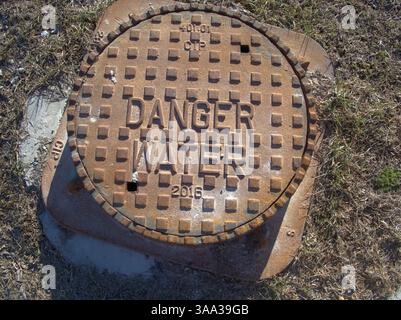 Message de sécurité clairement coulé dans le métal avertit les résidents de respecter les dangers cachés de l'infrastructure sous leurs pieds Banque D'Images