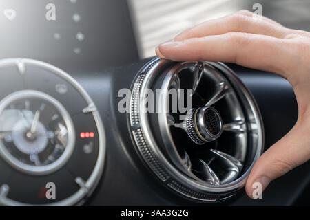 Une main ajuste doucement une bouche d'aération élégante et élégante pour assurer un confort optimal et un contrôle de la température efficace. Banque D'Images