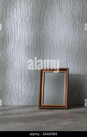 Cadre photo vide sur un fond gris. Cadre en bois avec ornement doré. Placez votre image dans le cadre. Copier l'espace. Banque D'Images