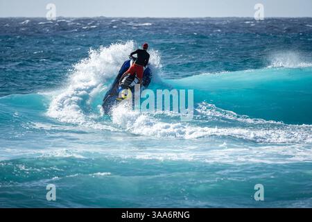 Homme en recherche et sauvetage ski océanique s'écrasant à travers Blue Ocean Wave Outbound to Sea - thème de l'opération d'intervention des sauveteurs Banque D'Images
