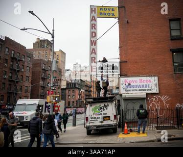 Les ouvriers installent une enseigne C.S. Brown Co. sur la quincaillerie Kove Bros. à Chelsea à New York le samedi 22 mars 2025. (© Richard B. Levine) Banque D'Images