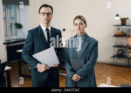 Portrait d'un couple d'affaires en tenue formelle regardant la caméra tout en travaillant ensemble au bureau Banque D'Images