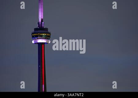 La terrasse d'observation de la Tour CN de Toronto éclairée en rouge et en violet la nuit présente les détails architecturaux de ce monument emblématique du Canada Banque D'Images