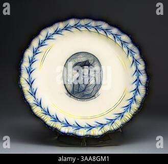 Une plaque décorative avec une bordure florale bleue complexe et un portrait central d'un homme portant un chapeau, rendu dans les moindres détails. Le design allie élégance et art, mettant en valeur un mélange de savoir-faire artisanal et de référence historique., Art classique avec une touche moderne réinventée par Artotop, basé sur plate, c. 1790, anglais pour le marché américain, Leeds, Angleterre, Creamware, Diam. 24,3 cm (9 9/16 po) Banque D'Images