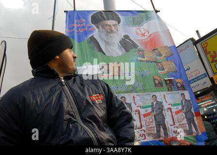 14 décembre 2006 - Téhéran, IRAN - un iranien regarde par-dessus son devoir la grande bannière des candidats municipaux de Téhéran et la photo du chef suprême de l'Iran, l'ayatollah Ali Khamenei, sur la place Enqelab. Les élections municipales iraniennes et les élections de l'Assemblée des experts se tiendront simultanément le 15 décembre. Photo de Siavash Habibollahi/ZUMA Press. Banque D'Images