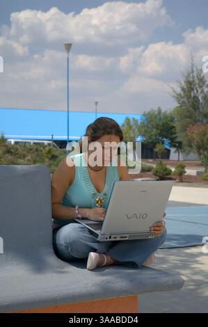 21 avril 2006 ; Queretaro, Queretaro, MEXIQUE ; Mayra Ponce, étudiante à l'Universidad Tecnologica de Queretaro, travaille sur son ordinateur portable alors qu'elle est assise à l'extérieur dans un patio de l'université. Bombardier Corporation forme les étudiants en technologie comme elle en vue d’un éventuel emploi futur dans l’usine qu’ils construisent à Queretaro. Crédit obligatoire : photo de Keith Dannemiller/ZUMA KPA. (©) Copyright 2006 par Keith Dannemiller Banque D'Images