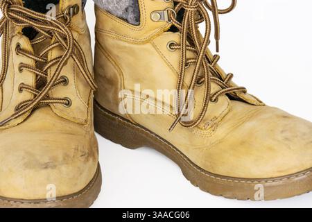 Bottes de randonnée en cuir jaune vintage avec lacets dans un look usé. Beige utilisé des chaussures militaires avec des semelles épaisses. Isolé sur fond blanc. Studio LIG Banque D'Images