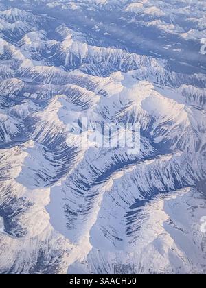 Prise de vue aérienne capturant une vaste chaîne de montagnes enneigée avec des sommets nets et un terrain accidenté. Paysage hivernal à couper le souffle vu d'en haut. Banque D'Images
