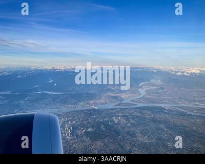 Paysage urbain et rivière sinueuse vus de la fenêtre de l'avion avec chaînes de montagnes et disposition urbaine s'étendant en dessous. Banque D'Images