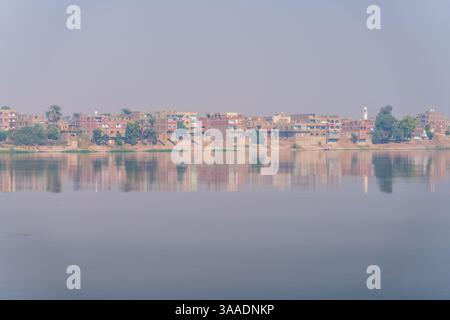 Petite ville d'AZ Zawayah dans le Gouverneur de Qena en Egypte au bord du fleuve Nil avec brume brumeuse de chaleur au-dessus de la rivière Banque D'Images