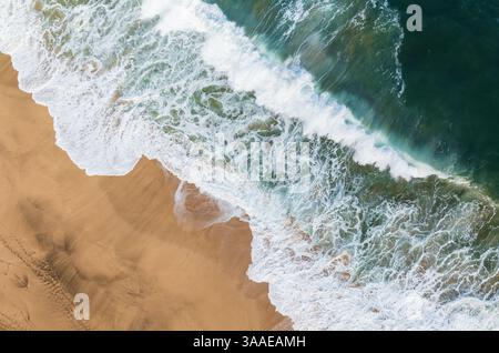 Une photo en grand angle capture les puissantes vagues de l'océan qui s'écrasent sur la rive sablonneuse de la plage de Lumahai à Kauai, Hawaï. Banque D'Images