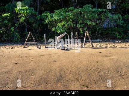 Le mot 'Aloha' est écrit en utilisant du bois flotté et d'autres matériaux naturels sur une plage de sable de Kauai avec la végétation en arrière-plan. Banque D'Images