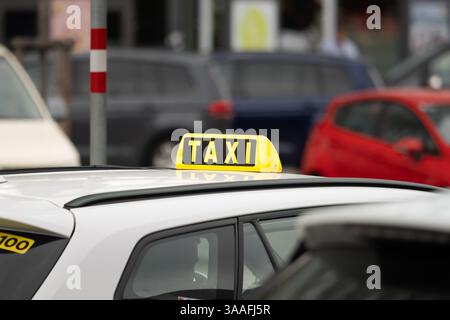 Signe de taxi sur un gros plan de voiture en Autriche. Chauffeur en attente dans une zone urbaine très fréquentée. Le symbole jaune est monté sur le toit. Service de transport urbain. Banque D'Images