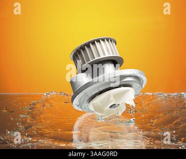 Pièces auto, pompe de refroidissement moteur dans de l'eau splash sur fond dégradé orange Banque D'Images