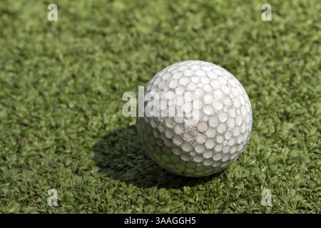 Vieille balle de golf sale rayée sur gazon artificiel Banque D'Images
