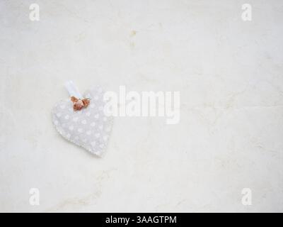 Pochette en tissu en forme de coeur avec petits coeurs imprimés et petite fleur de rose sur fond beige avec espace copie Banque D'Images