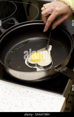 Œuf frit en forme coeur sur pan Banque D'Images