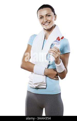 Belle femme souriante portant des vêtements de sport tenant une bouteille d'eau ouverte Banque D'Images