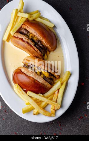 Burger avec des frites dans une sauce au fromage Banque D'Images