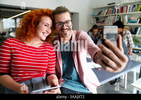 Sympathique collègue multiethnique heureux homme et femme s'amusant avec smartphone, travaillant ensemble Banque D'Images