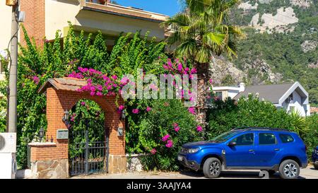 Rue dans la ville ou village de Turunc, Turquie, sur la côte méditerranéenne. Entrée de la maison avec portail en fer forgé et arc en briques rouges avec bougai fleuri Banque D'Images