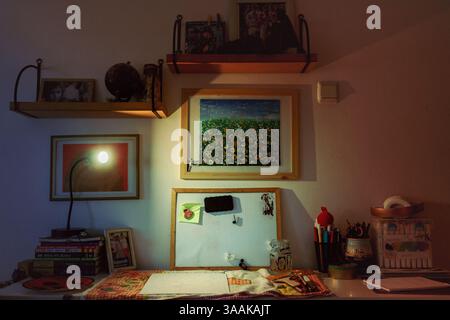 Cacak, Serbie - 26 février 2025 : Détails d'une chambre d'enfants, une table avec des fournitures de peinture, des photos de famille et des œuvres d'art pour enfants sur les étagères. Banque D'Images