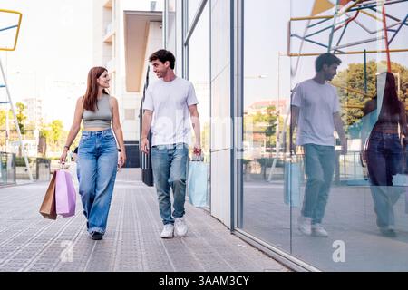 un homme et une femme marchant avec des sacs à provisions Banque D'Images