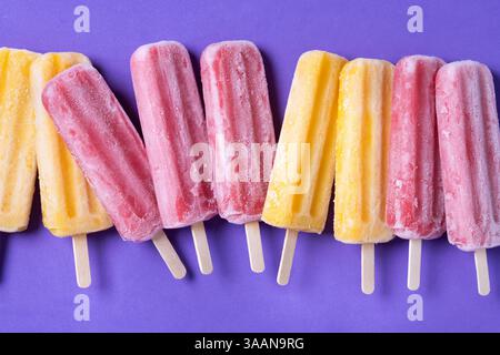 Popsicles orange et rose sur fond violet Banque D'Images