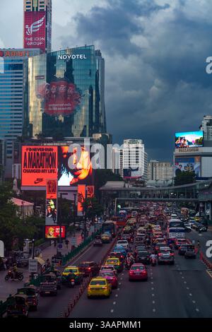 Cette image dramatique du soir capture la circulation animée sur Ratchadamri Road, Bangkok, Thaïlande, sous un ciel nuageux et de mauvaise humeur. La scène comporte un mix Banque D'Images