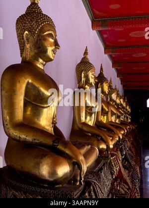 Cette image sereine capture une rangée de statues de Bouddha dorées à Wat Phra, Bangkok, Thaïlande, assis dans des poses méditatives. Les détails complexes du STA Banque D'Images