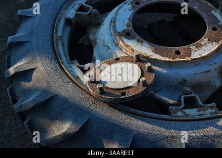 Vieille roue de tracteur reposant sur un sol givré comme ferraille Banque D'Images