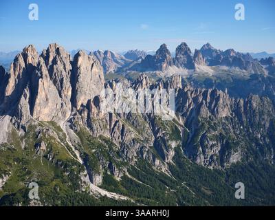 VUE AÉRIENNE. Cadini Group à gauche, au loin ; Tre Cima di Lavaredo. Auronzo di Cadore, Province de Belluno, Vénétie, Italie. Banque D'Images