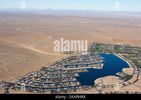 VUE AÉRIENNE. Développement de logements et un lac artificiel en contraste frappant avec le désert de Mojave environnant. Helendale, Californie, États-Unis. Banque D'Images