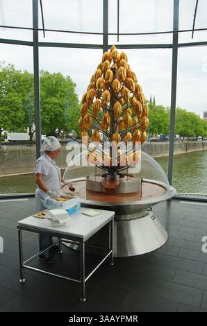 Cologne, Allemagne – 6 mai 2014. Fontaine de chocolat au Musée du chocolat de Cologne. Vue avec les gens et la promenade de la rivière en arrière-plan. Banque D'Images