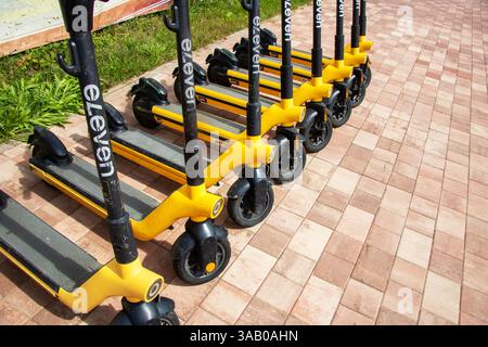 Biélorussie, Minsk - 18 juillet, 2024 : une rangée de scooters jaunes et noirs élégants est soigneusement garée dans un parking spacieux, mettant en valeur t urbain moderne Banque D'Images