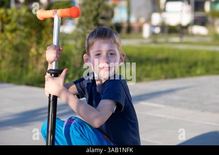Garçon diabétique en scooter, souriant à la caméra, capteur de glucose visible. Banque D'Images