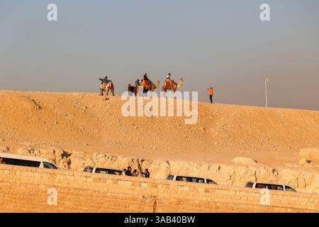 Touristes sur une balade à dos de chameau dans les sables du désert du complexe pyramidal de Gizeh en Egypte Banque D'Images