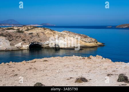 Milos, Grèce - 29 septembre 2024 : touristes sur les falaises au-dessus des grottes de Papafragas avec des eaux bleues claires et un paysage rocheux sous un ciel lumineux Banque D'Images